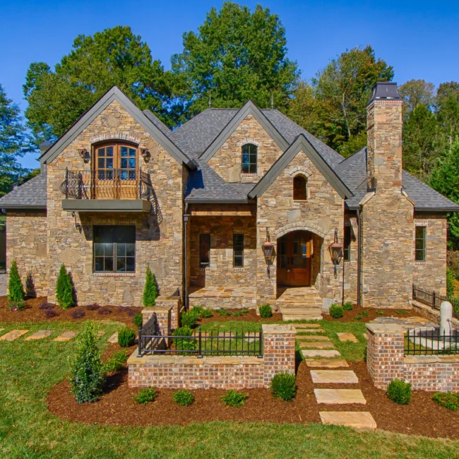 Stone exterior with arched entry, balcony and steep gabled roof in European Villa, a custom home by Mike Stevens Homes