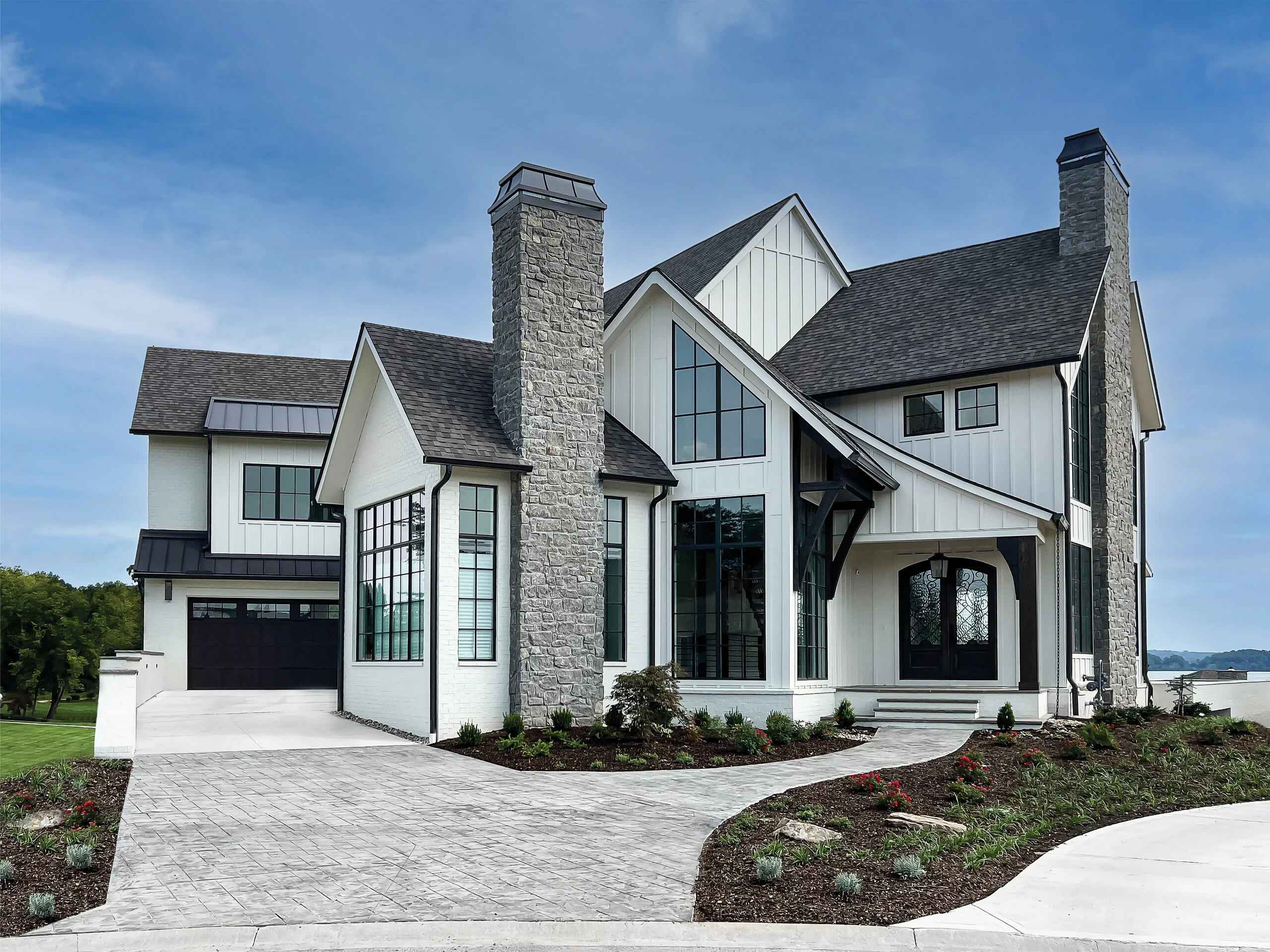 Front of white farmhouse with stone chimney and board-and-batten in Luxury Lakehome, a custom home by Mike Stevens Homes