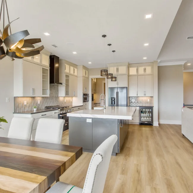 Open kitchen with gray island and wood-top dining table in Contemporary Luxury, a custom home by Mike Stevens Homes