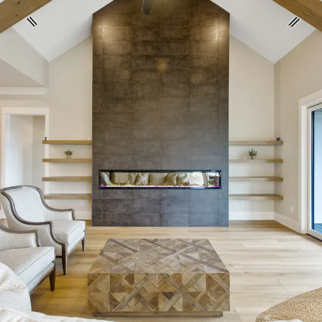 Gas fireplace wall beside floating shelves and chair in Contemporary Luxury, a custom home by Mike Stevens Homes
