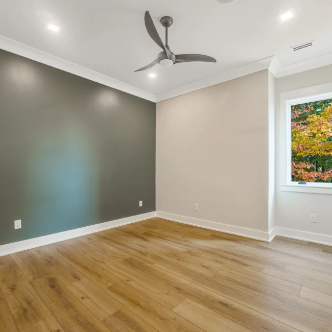 Room with deep green accent wall and ceiling fan in Contemporary Luxury, a custom home by Mike Stevens Homes