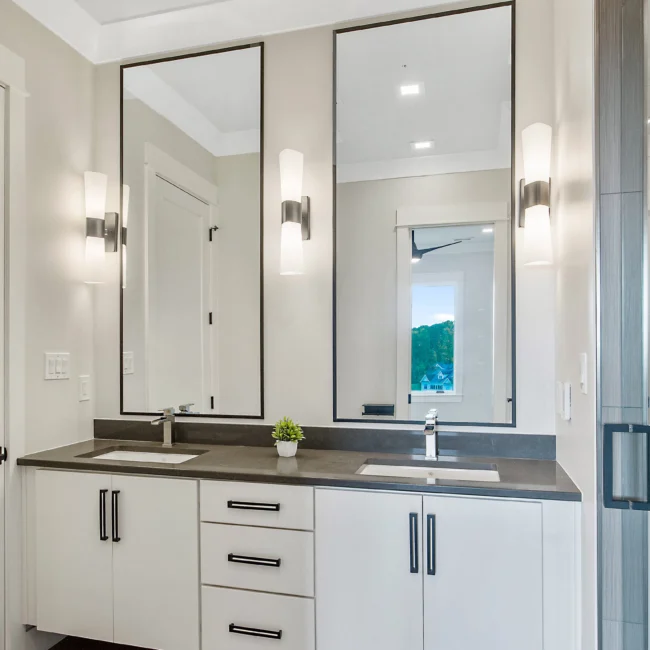 Dual-sink vanity with wall sconces and tall mirrors in Contemporary Luxury, a custom home by Mike Stevens Homes