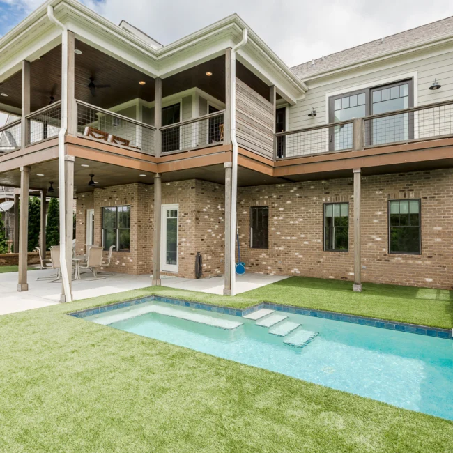 Rear covered deck with in-ground pool and lawn in Urban Farmhouse, a custom home by Mike Stevens Homes
