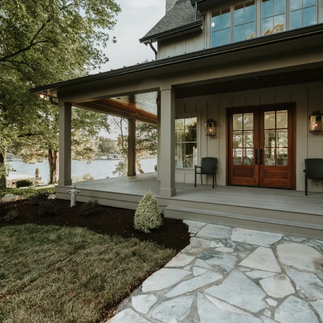 Covered porch with dark wood french doors and flagstone walk in Island Farmhouse, a custom home by Mike Stevens Homes