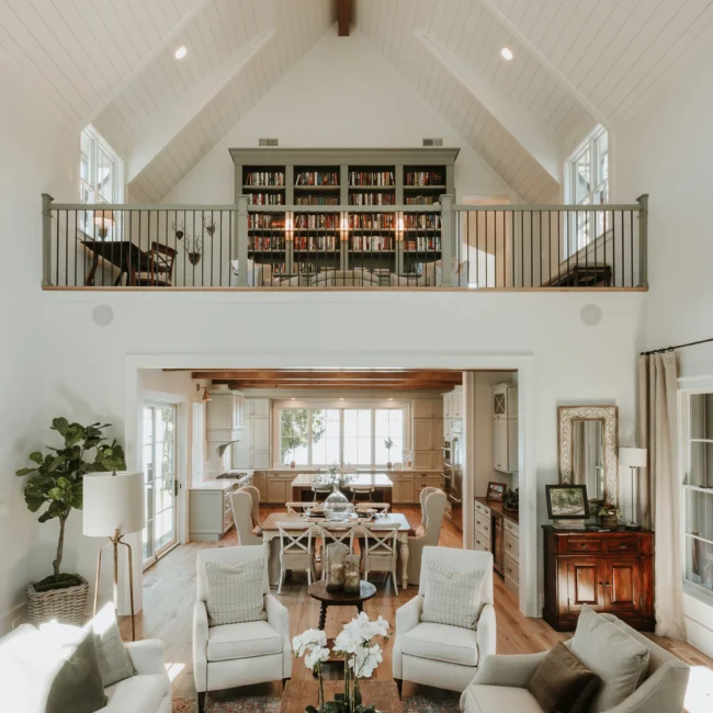 Two-story great room with loft library overhead in Island Farmhouse, a custom home by Mike Stevens Homes