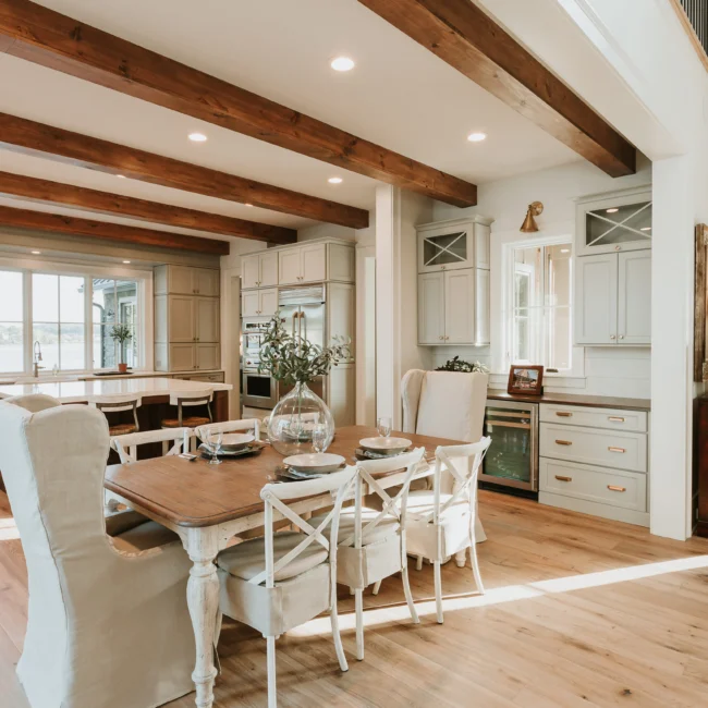 Kitchen with exposed beams and farmhouse dining table in Island Farmhouse, a custom home by Mike Stevens Homes