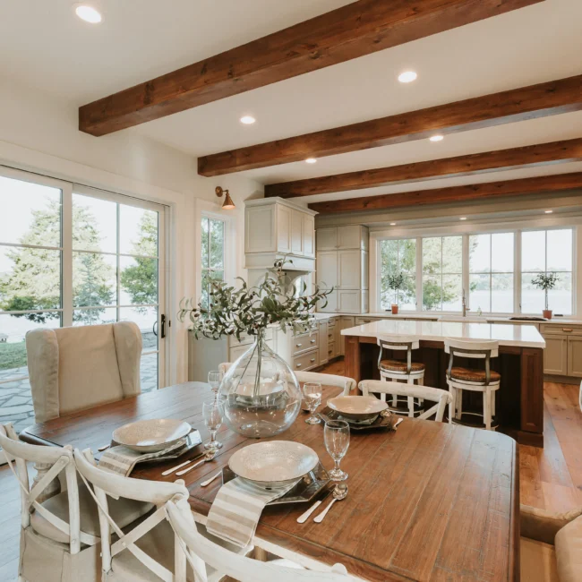 Dining area with farmhouse table beside kitchen island in Island Farmhouse, a custom home by Mike Stevens Homes