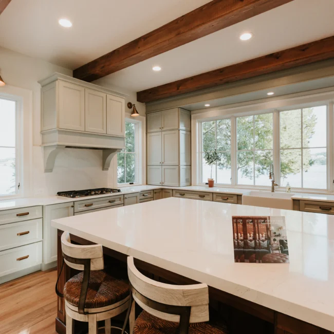 Kitchen with cream cabinetry and oversized range hood in Island Farmhouse, a custom home by Mike Stevens Homes