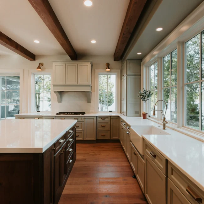 Kitchen with dark-stained island and cream cabinets in Island Farmhouse, a custom home by Mike Stevens Homes