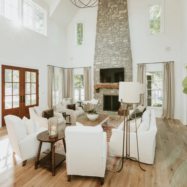 Living room with stone fireplace and white sofas in Island Farmhouse, a custom home by Mike Stevens Homes