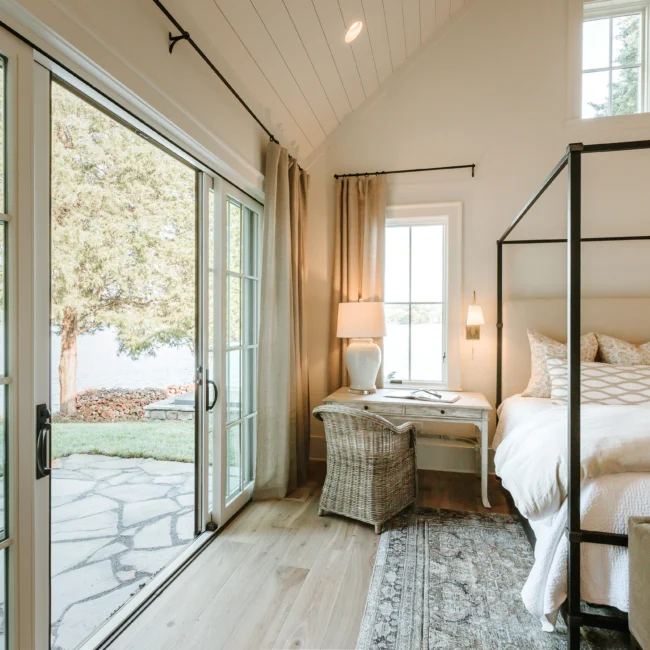 Bedroom with canopy bed and patio doors to stone patio in Island Farmhouse, a custom home by Mike Stevens Homes