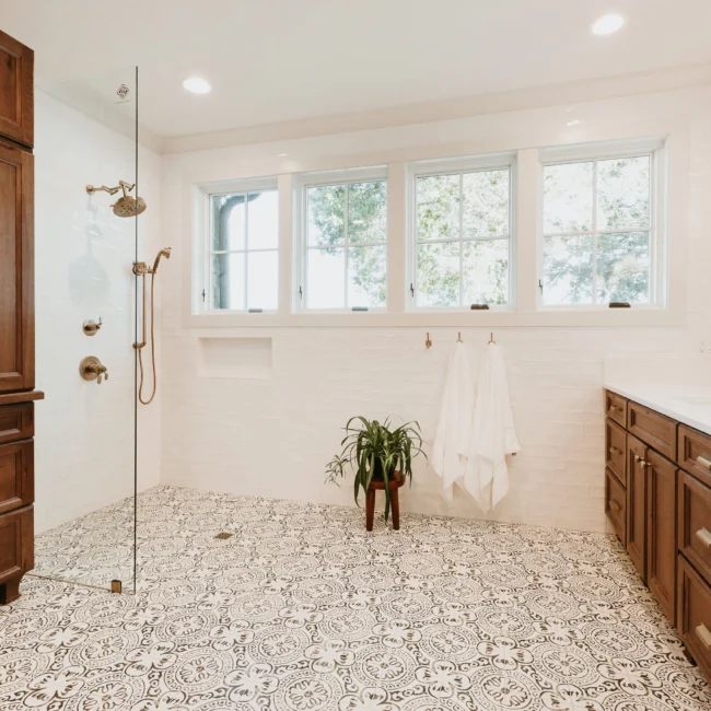 Walk-in shower with patterned tile and tall windows in Island Farmhouse, a custom home by Mike Stevens Homes