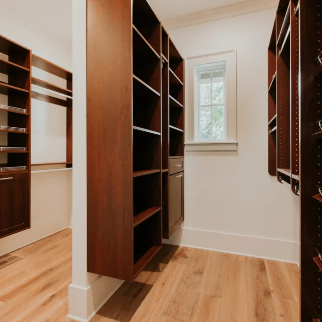 Walk-in closet with open wood shelving in Island Farmhouse, a custom home by Mike Stevens Homes
