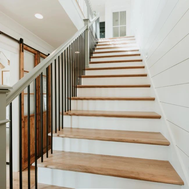 Staircase with wood treads and black iron railing in Island Farmhouse, a custom home by Mike Stevens Homes
