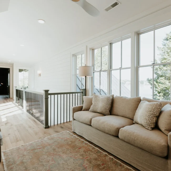 Upstairs sitting area with sofa and tall windows in Island Farmhouse, a custom home by Mike Stevens Homes
