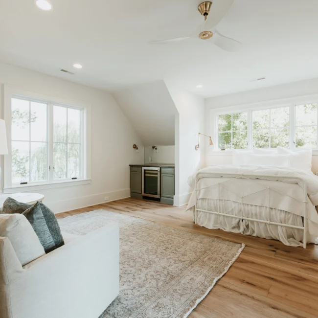 Bedroom with sloped white ceiling and window views in Island Farmhouse, a custom home by Mike Stevens Homes