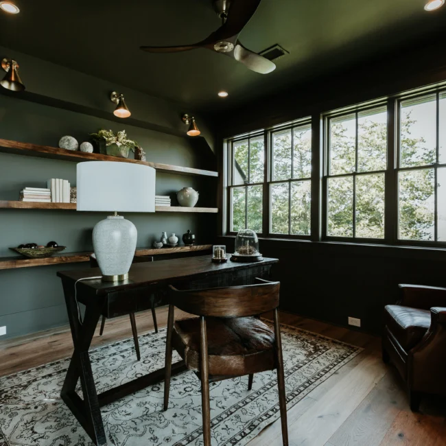 Home office with dark green walls and black desk in Island Farmhouse, a custom home by Mike Stevens Homes