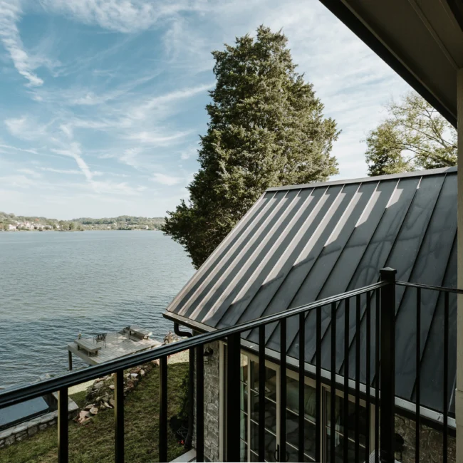 Metal-roof balcony with iron railing and water view in Island Farmhouse, a custom home by Mike Stevens Homes