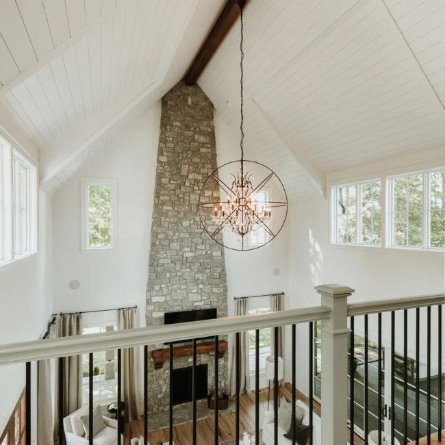 Vaulted great room with stone fireplace and chandelier in Island Farmhouse, a custom home by Mike Stevens Homes