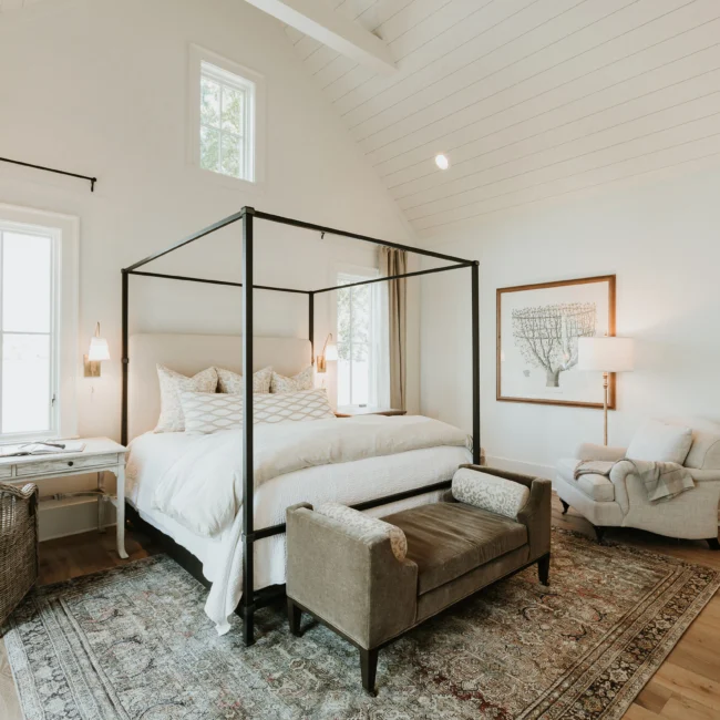 Bedroom with canopy bed and vaulted white ceiling in Island Farmhouse, a custom home by Mike Stevens Homes