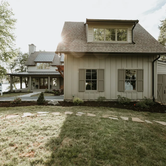 Gabled farmhouse exterior with dormer and mature trees in Island Farmhouse, a custom home by Mike Stevens Homes