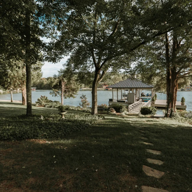 Backyard with gazebo, stone steps, and shade trees in Island Farmhouse, a custom home by Mike Stevens Homes