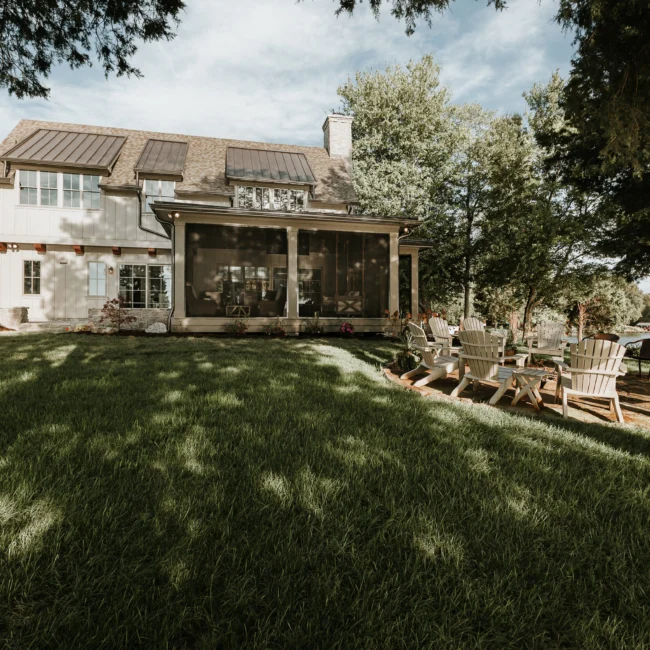 Rear of home with screened porch and sloping lawn in Island Farmhouse, a custom home by Mike Stevens Homes