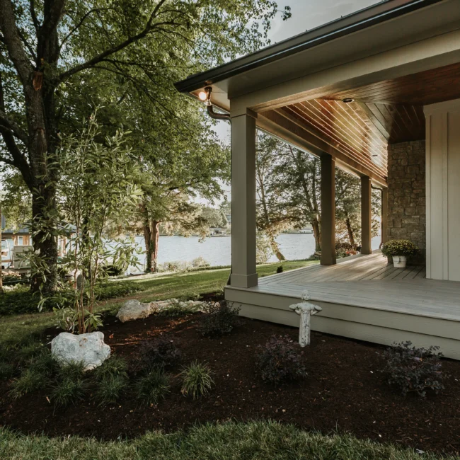 Covered porch with tongue-and-groove ceiling and stone column in Island Farmhouse, a custom home by Mike Stevens Homes