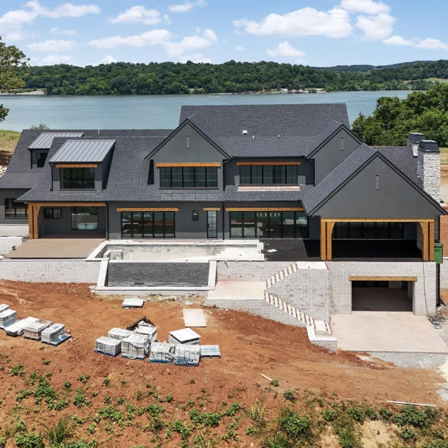 Aerial of lakeside pool site and stone steps on a graded slope in Edgewater Estate, a custom home by Mike Stevens Homes