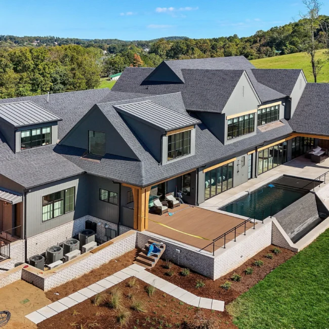 Aerial rear of home with covered terrace, pool and stone walls in Edgewater Estate, a custom home by Mike Stevens Homes