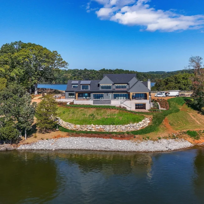 Aerial of lakefront home with stacked stone seawall above the water in Edgewater Estate, a custom home by Mike Stevens Homes