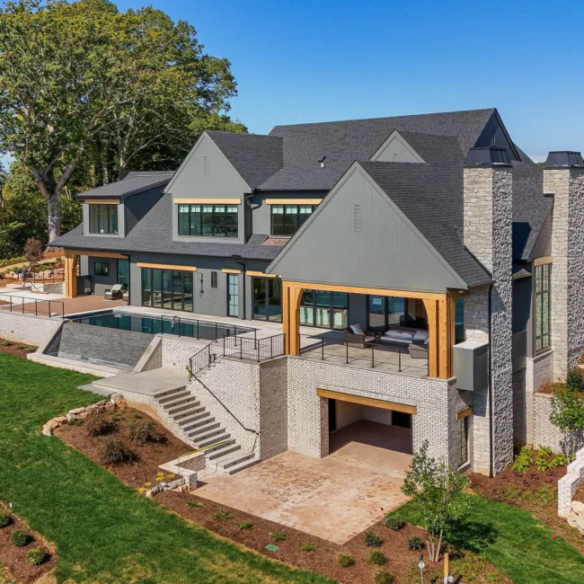 Aerial rear view of stone and timber home with covered terrace in Edgewater Estate, a custom home by Mike Stevens Homes