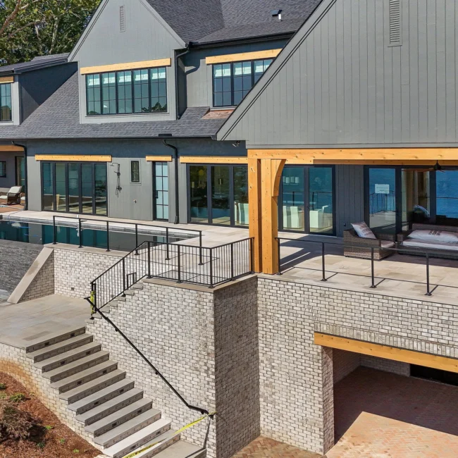 Rear terrace with black railing, stone steps and timber patio in Edgewater Estate, a custom home by Mike Stevens Homes