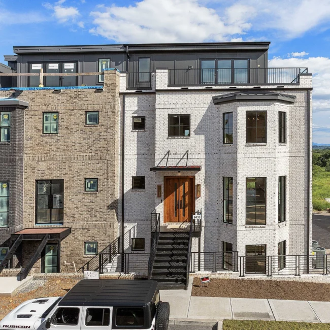 Multi-story brick and stone townhome with exterior stair in The Terrace by Mike Stevens Homes