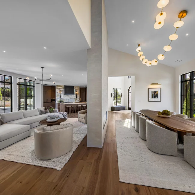 Open great room with curved chandelier, sectional sofa and dining table in The Sanctuary, a custom home by Mike Stevens Homes