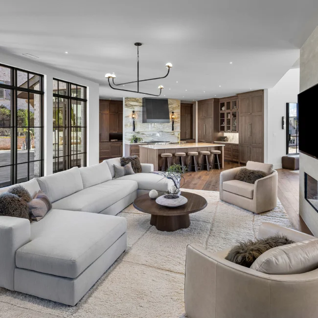 Great room with white sectional, round coffee table and fireplace wall in The Sanctuary, a custom home by Mike Stevens Homes