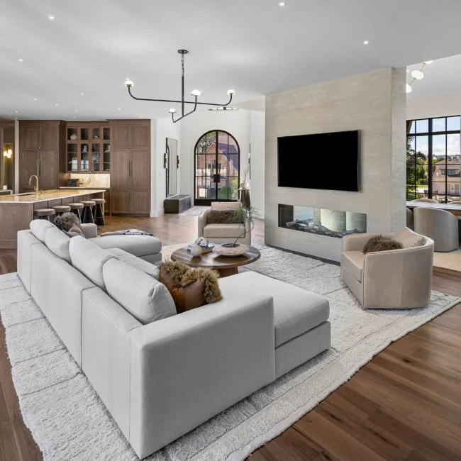 Living room with gray sectional facing a linear fireplace and TV wall in The Sanctuary, a custom home by Mike Stevens Homes
