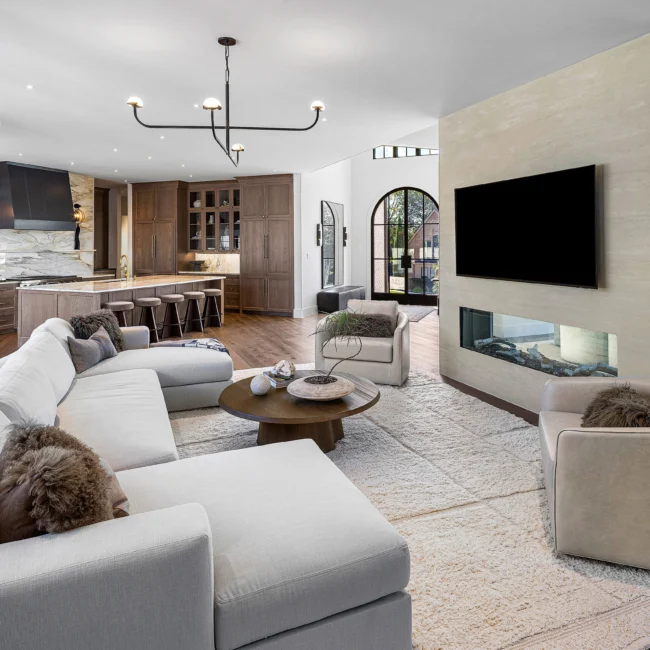 Living room with taupe sectional, wood coffee tables and wall-mounted TV in The Sanctuary by Mike Stevens Homes
