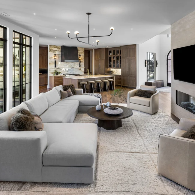 Living room angle with sectional, round walnut coffee table and stone fireplace in The Sanctuary by Mike Stevens Homes
