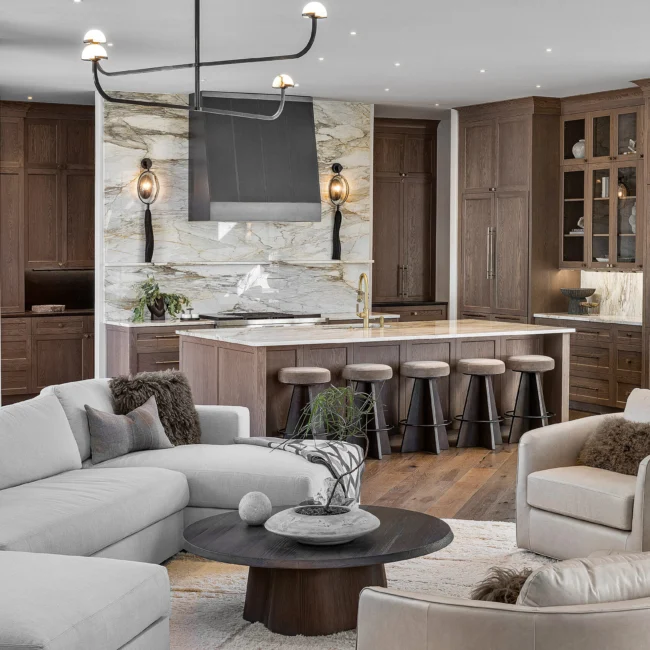 Kitchen island and bar seating viewed from living room with round walnut coffee table in The Sanctuary by Mike Stevens Homes