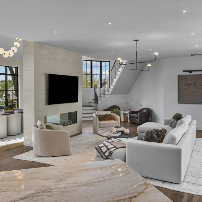 Two-story great room with stone fireplace, stair and chandelier in The Sanctuary, a custom home by Mike Stevens Homes