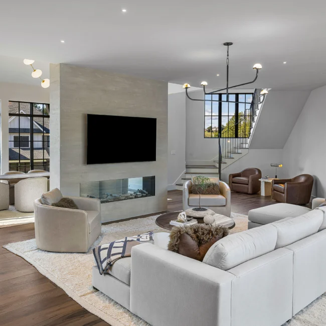 Great room with floating staircase, black window grid and sofa grouping in The Sanctuary, a custom home by Mike Stevens Homes