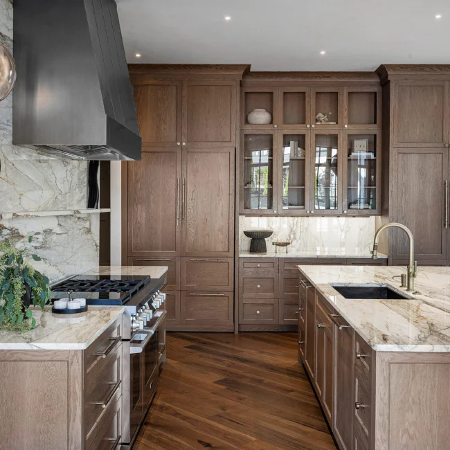 Kitchen with walnut cabinets, glass-front china cabinet and gold faucet in The Sanctuary, a custom home by Mike Stevens Homes