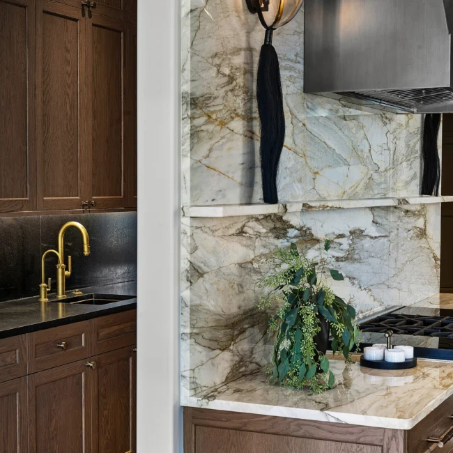 Close-up of gold faucet, marble backsplash and dark counter at wet bar in The Sanctuary by Mike Stevens Homes
