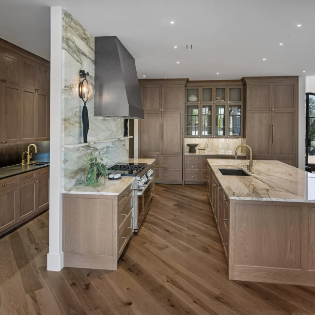 Kitchen with marble hood wall, walnut cabinets and island with quartz top in The Sanctuary by Mike Stevens Homes