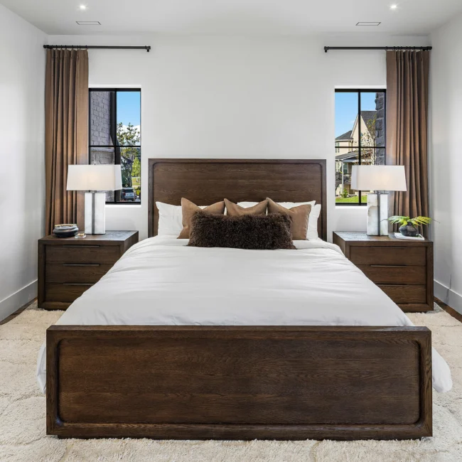 Primary bedroom with upholstered wood bed frame and matching nightstands in The Sanctuary by Mike Stevens Homes