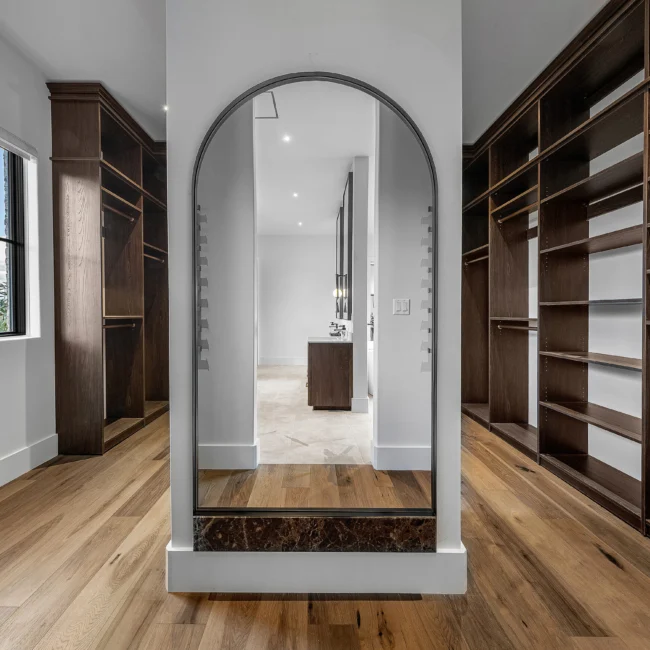 Walk-in closet with arched mirror and wood shelving in The Sanctuary, a custom home by Mike Stevens Homes
