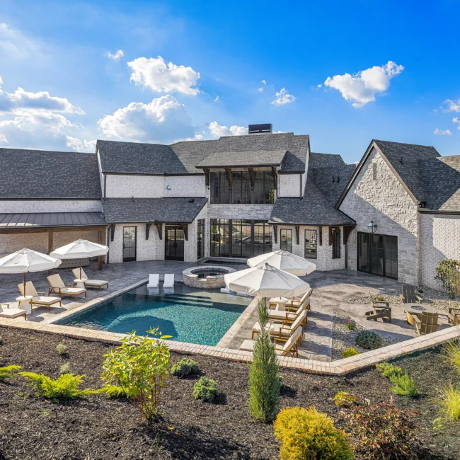 Rear elevation with pool, spa and landscaped beds beside stone home in The Sanctuary by Mike Stevens Homes