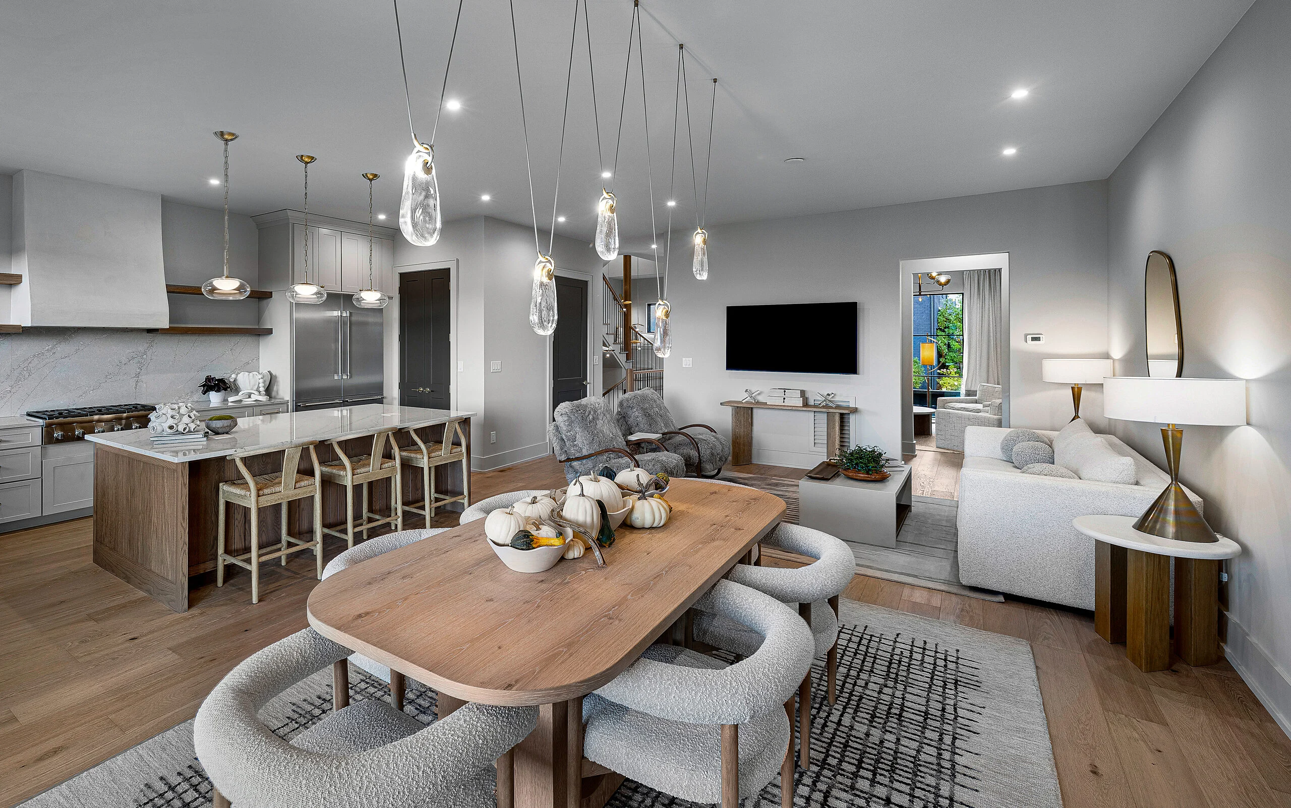 Open dining and living space with oval wood table and pendant lights in The Overlook by Mike Stevens Homes