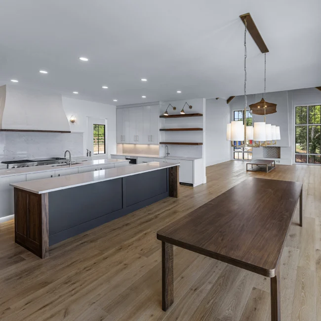 Open kitchen with walnut table, gray island and wood-look floors in Edgewater Estate, a custom home by Mike Stevens Homes